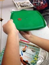 Magnet pulling a penny across a plastic lid